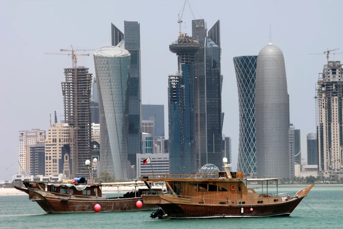 Construction cranes stand on the West Bay district skyline beyond moored boats in Doha, Qatar.