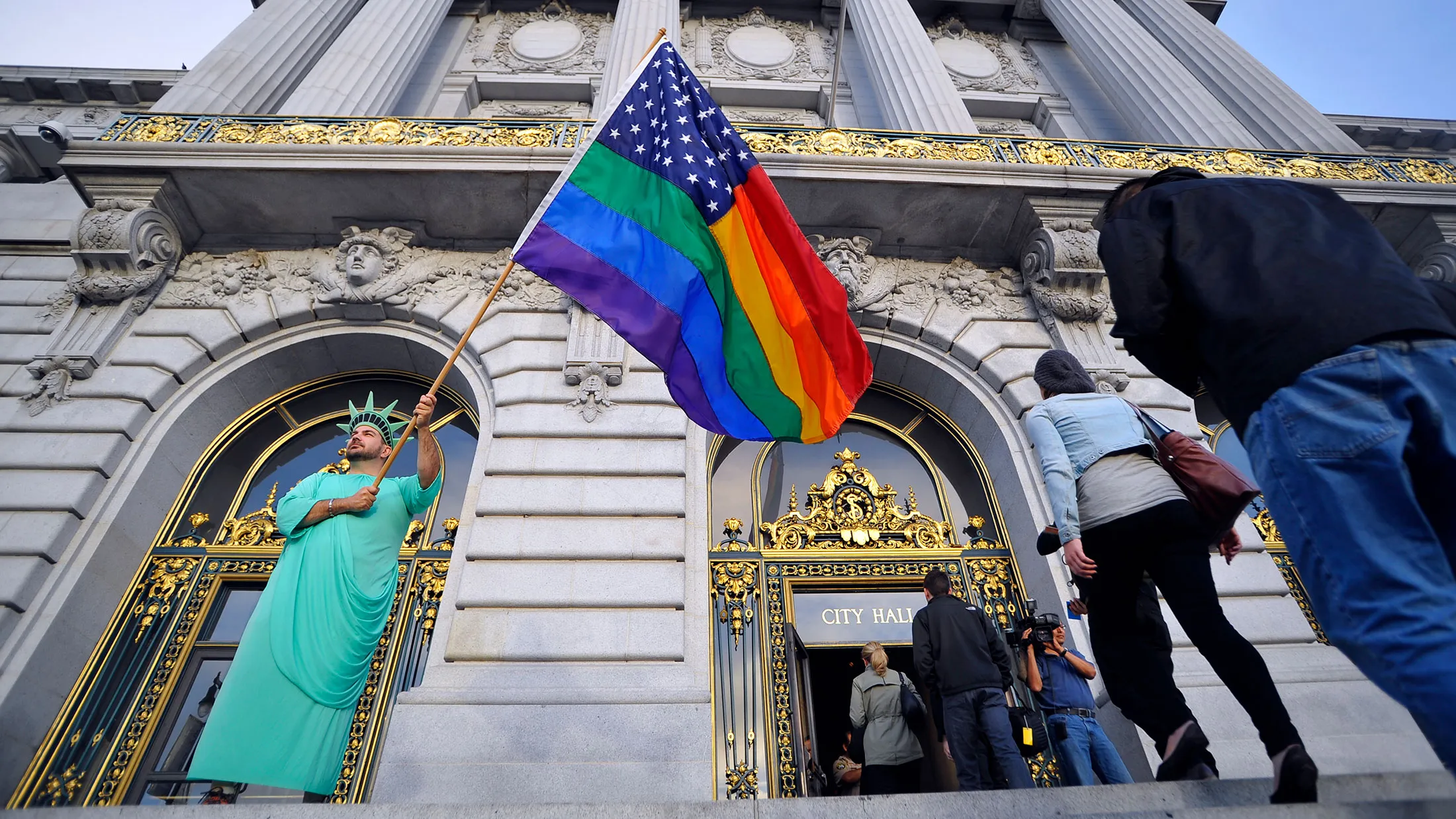 Nikolas Lemos waves a rainbow flag as people enter San Francisco City Hall in anticipation of the U.S. Supreme Court ruling on gay marriage on June 26, 2013.
