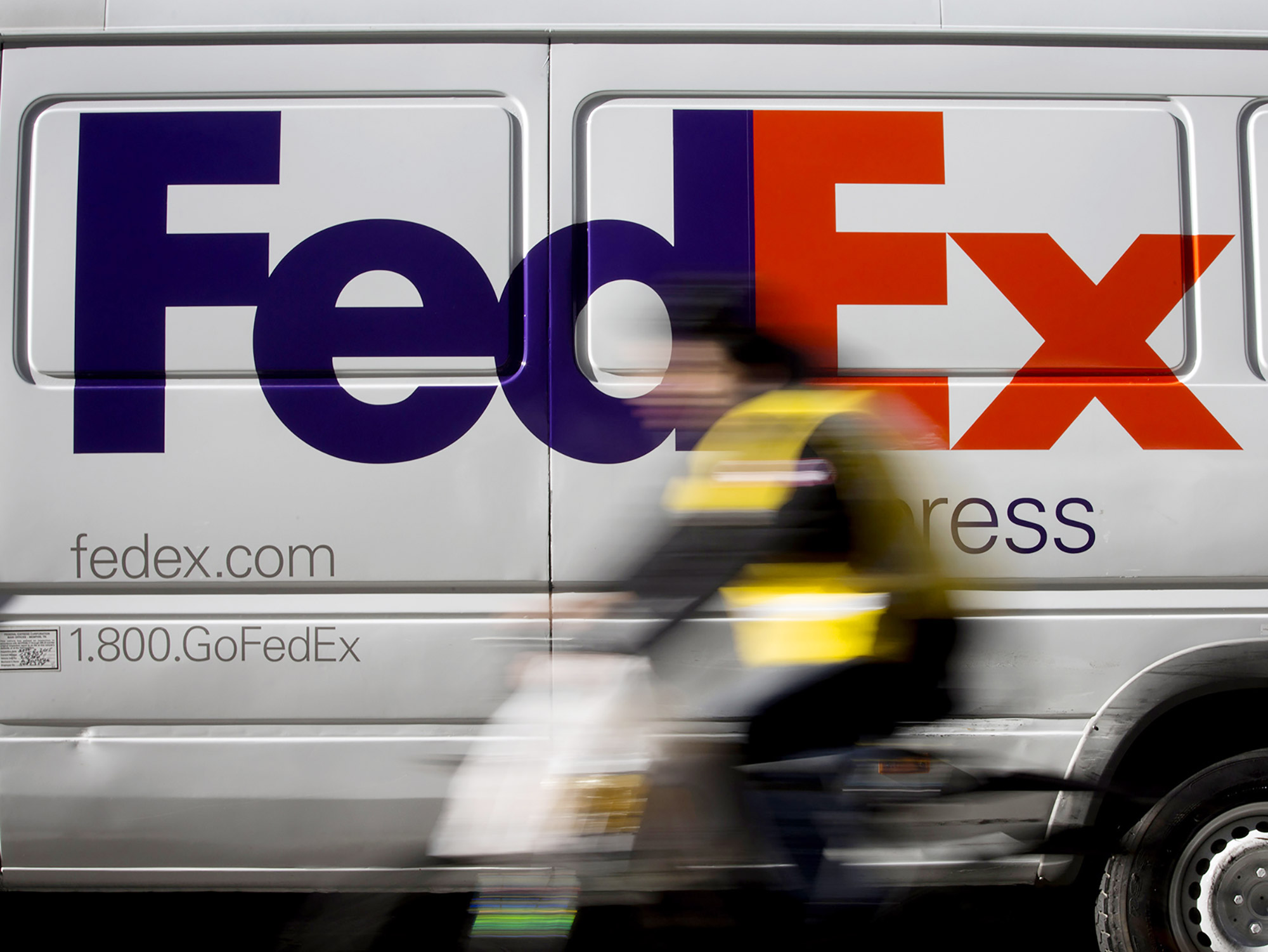 A bicyclist rides past a FedEx Corp. vehicle parked in the Midtown neighborhood of New York.&nbsp;