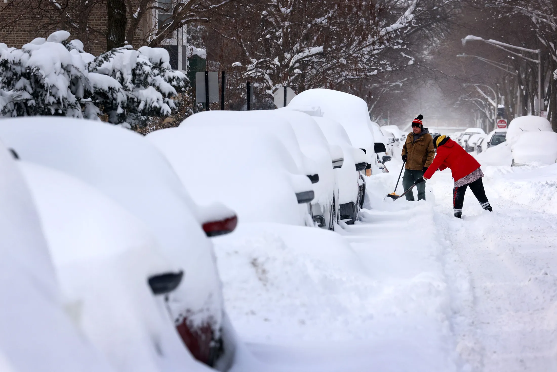 People work shovel snow along a residential street in Chicago, on Feb. 16.