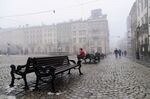 A man sits on a bench at Rynok square on a foggy day