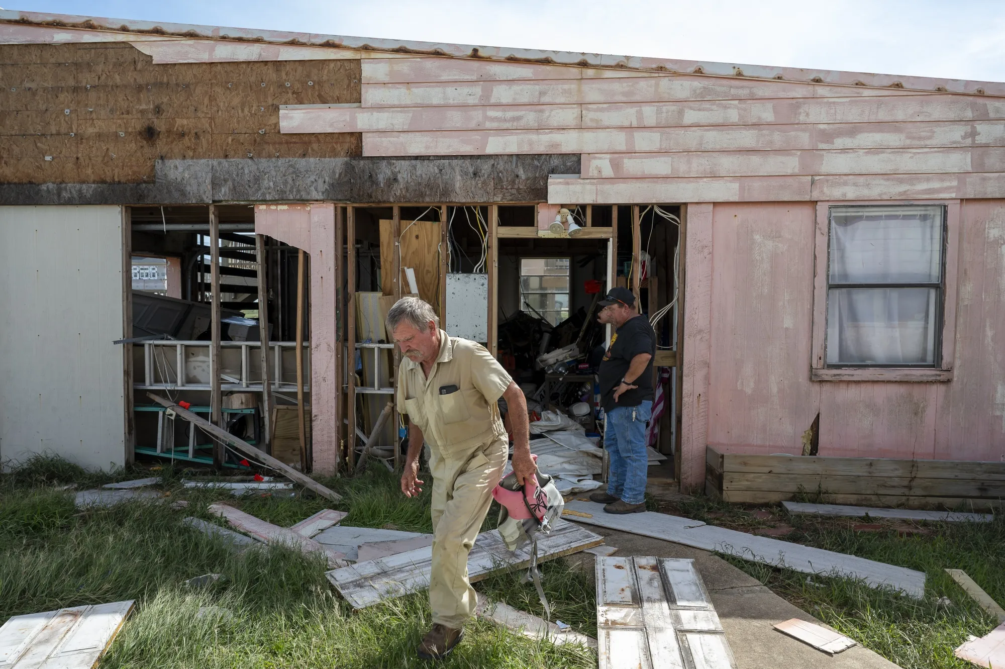 Residents around a damaged house after Hurricane Beryl made landfall in Sargent, Texas on July 8.&nbsp;