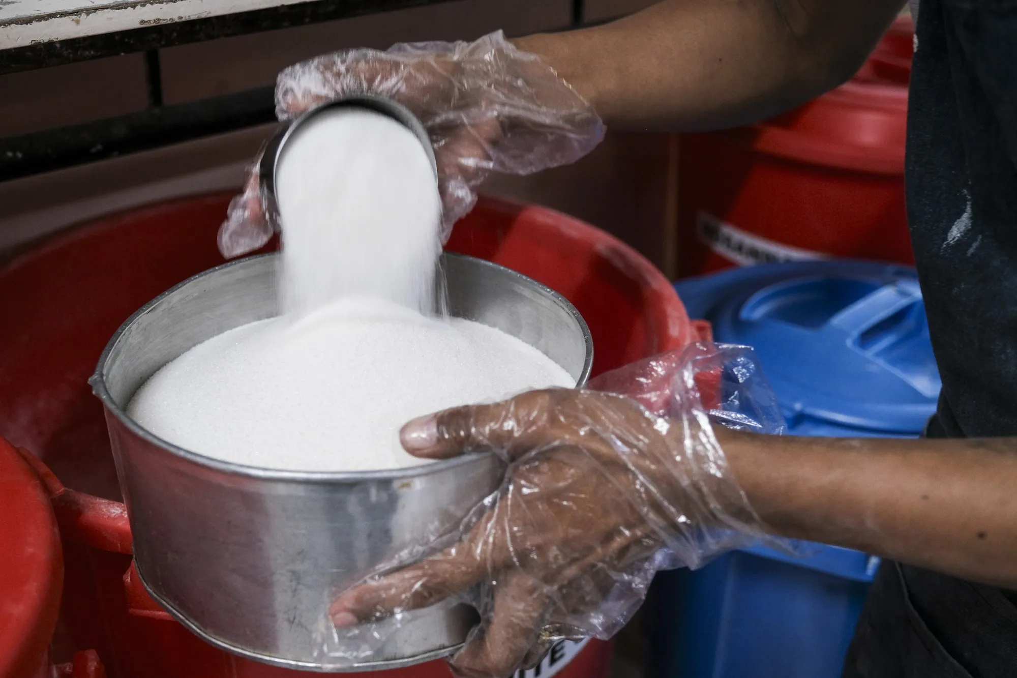 A baker measures refined sugar at a cafe's kitchen in Negros Occidental, the Philippines, on Tuesday, April 30, 2024.