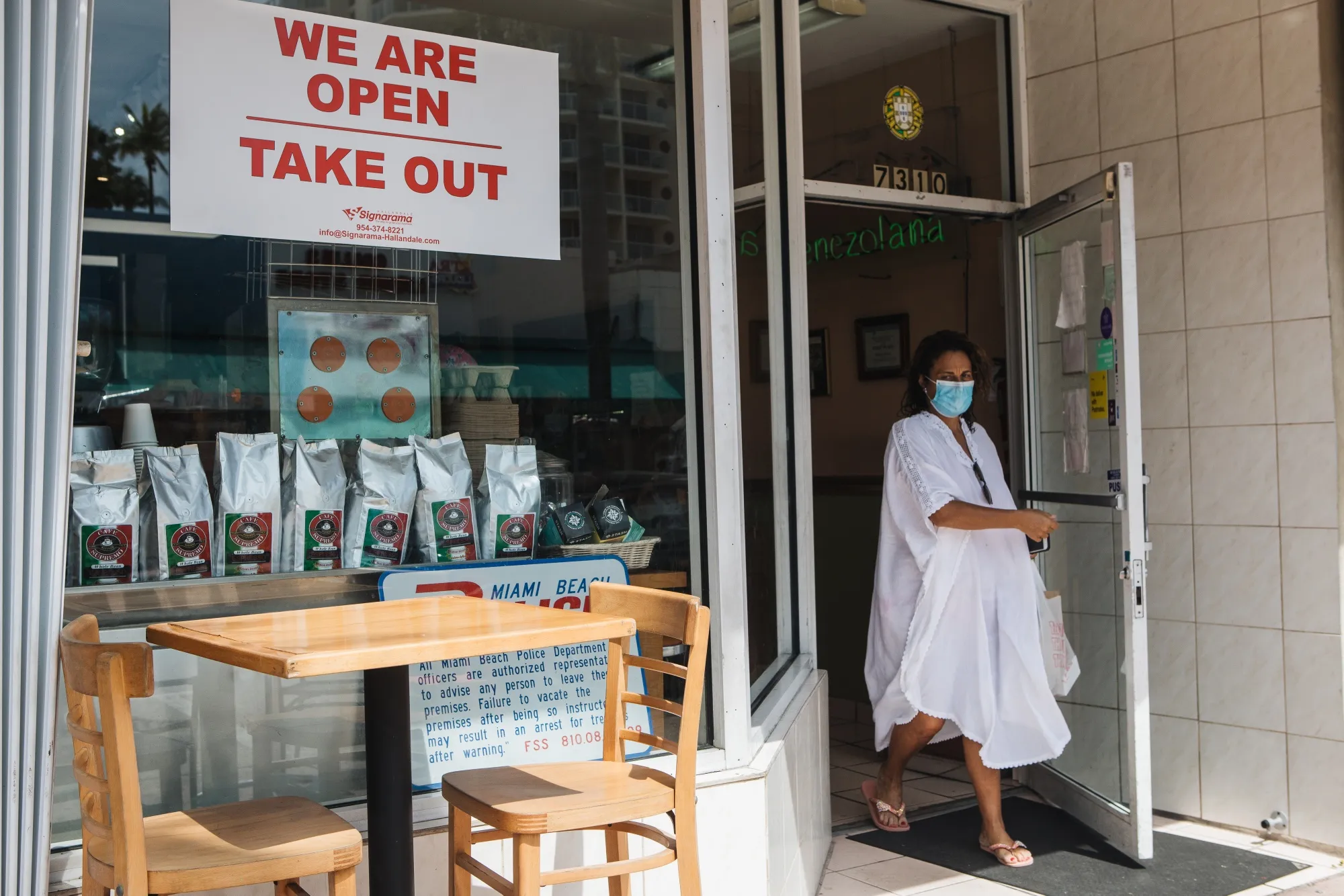 A customer wearing a protective mask exits a cafe in Miami.