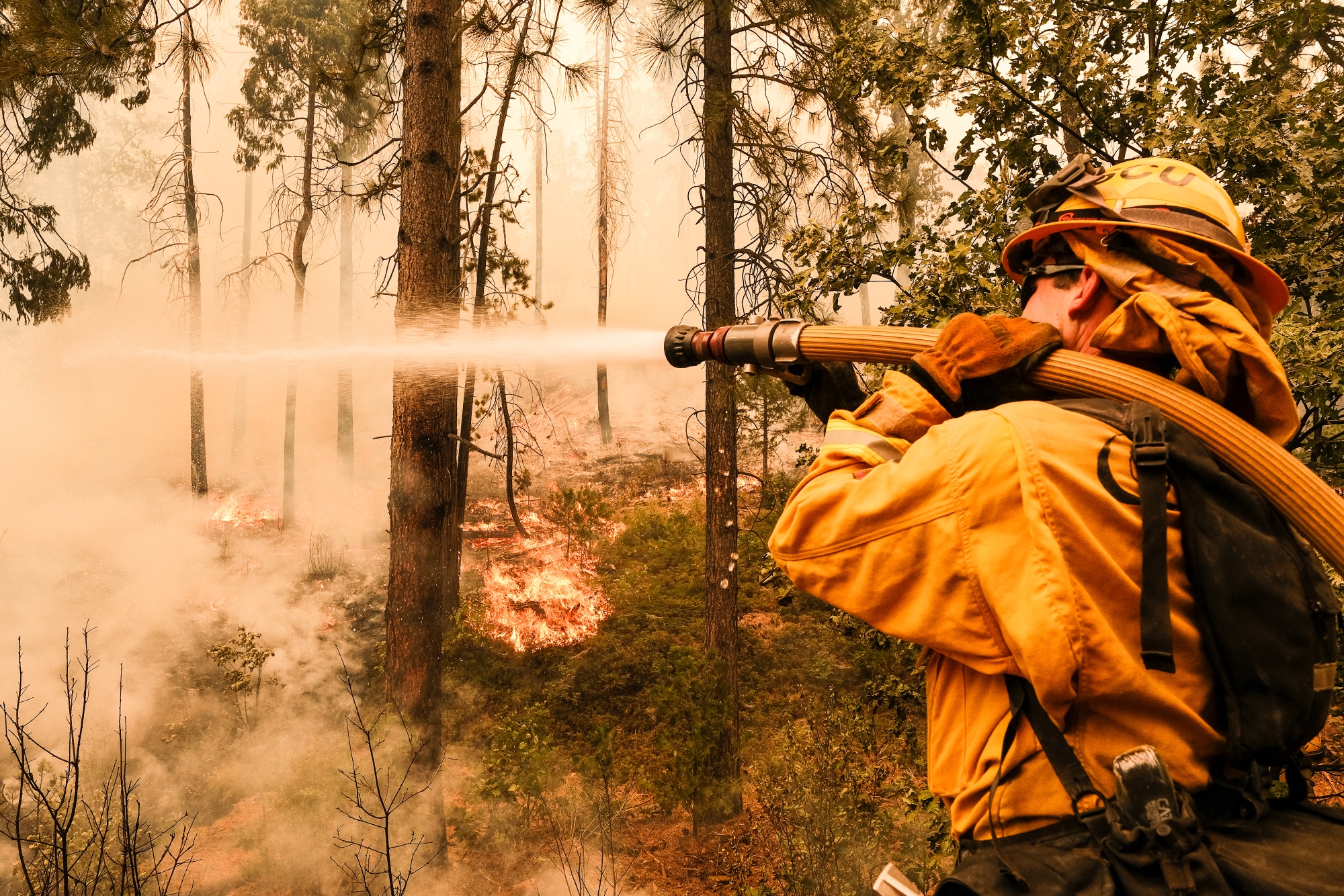 A firefighter works to control a backfire operation conducted to slow the advancement on a hillside during the Oak Fire in Mariposa County, California, on Sunday.
