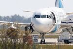 A man climbs out of the cockpit window an EgyptAir Airbus A-320 parked at the tarmac of Larnaca airport after being hijacked and diverted to Cyprus.
