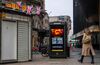 A woman walks past a closed souvenir stall and government messaging on a telephone booth on Oxford Street in London.