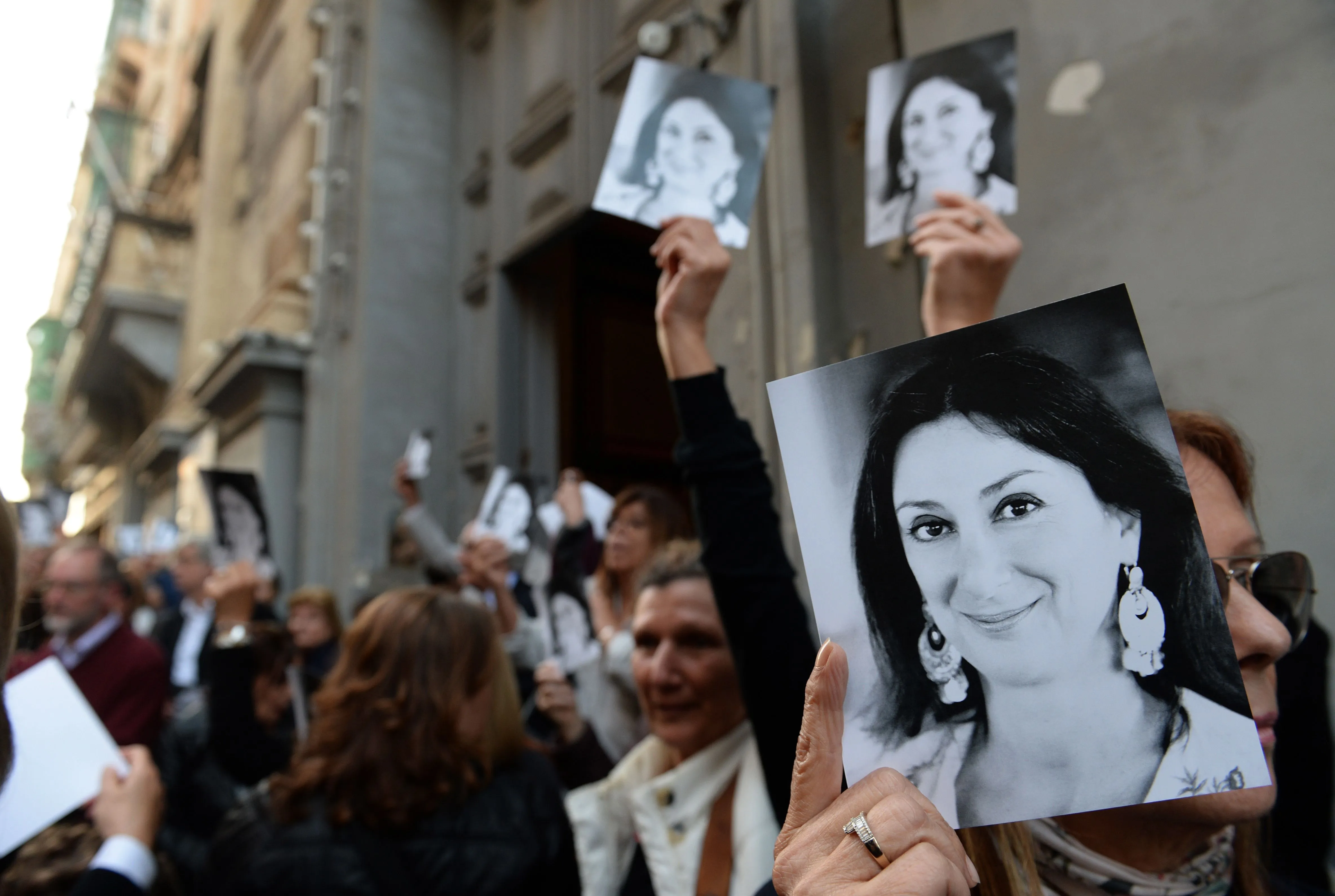 People hold photos of Daphne Caruana Galizia outside a church in Malta.