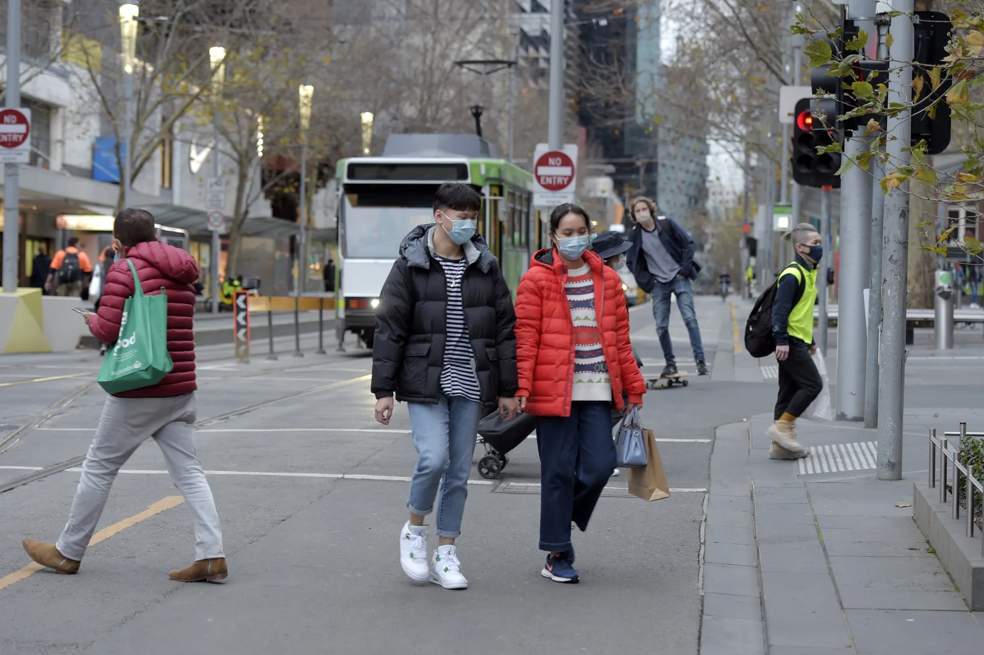 Pedestrians wearing protective masks cross an intersection in Melbourne, July 23.