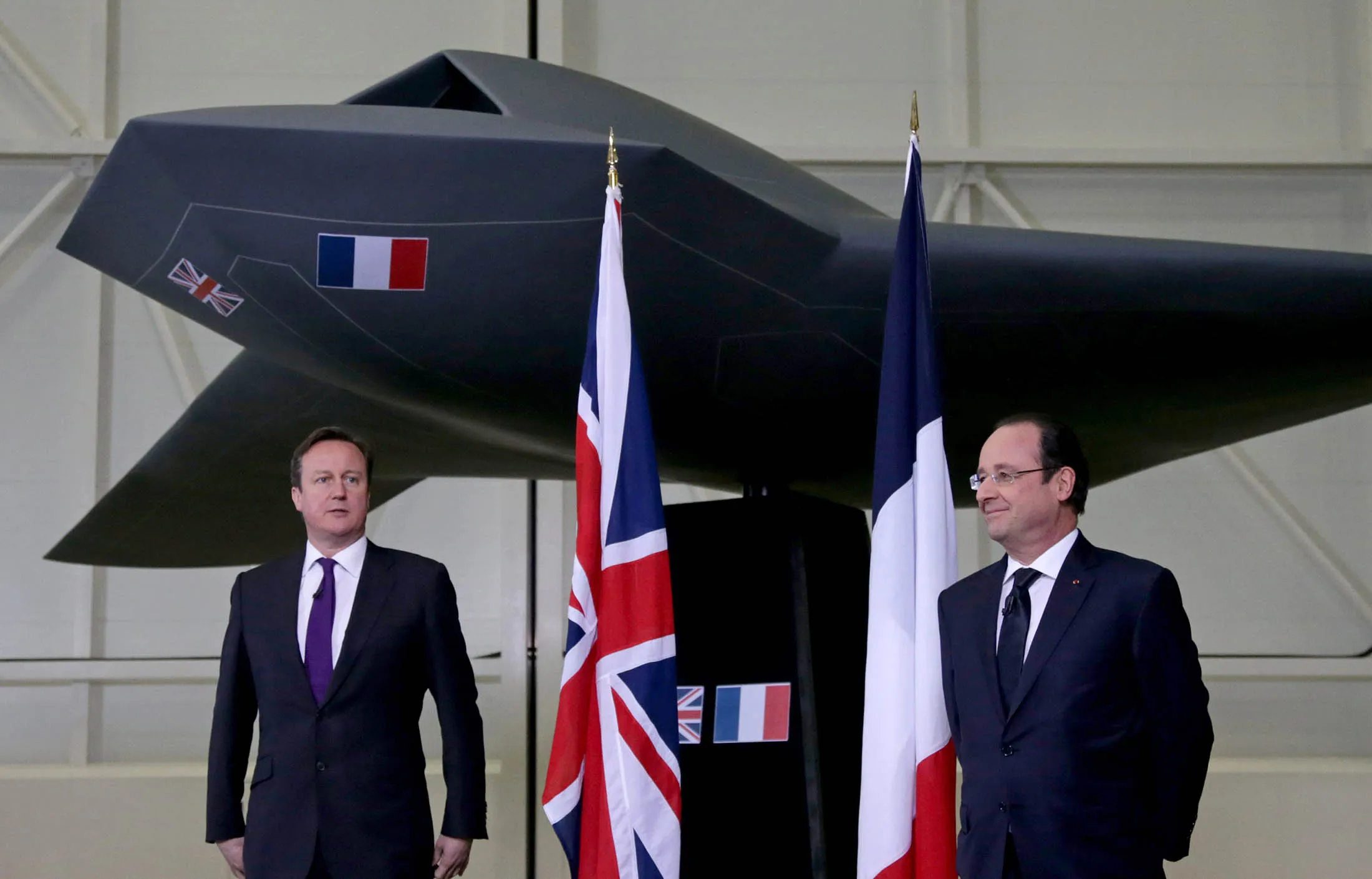 British Prime Minister David Cameron and French President Francois Hollande stand under a concept unmanned Future Combat Air System in 2014.
