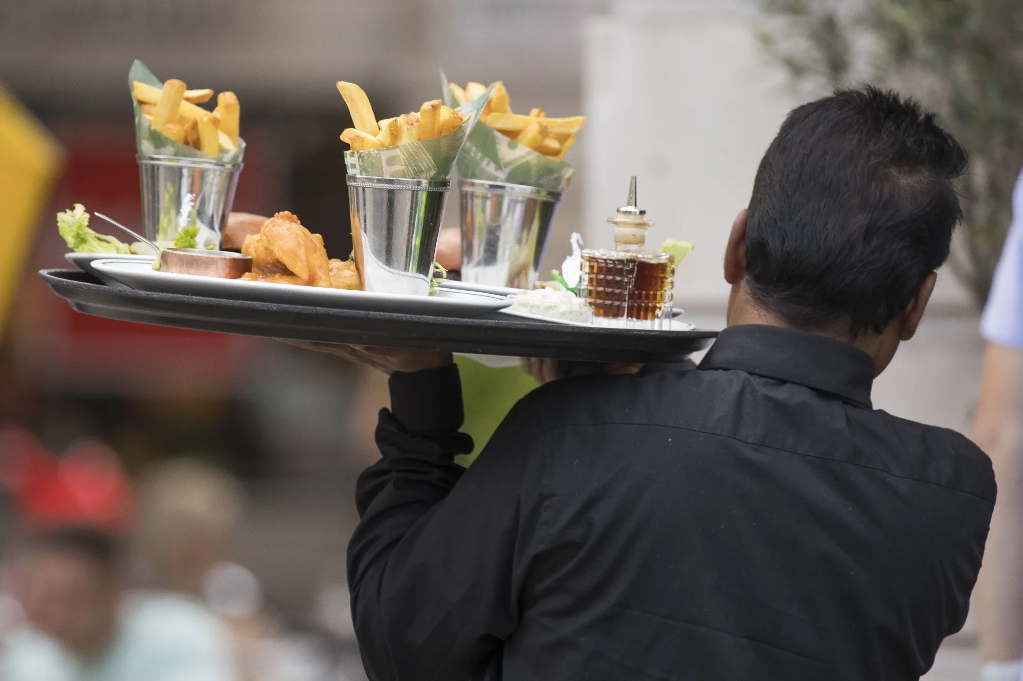 A waiter carries food to a table&nbsp;in London.