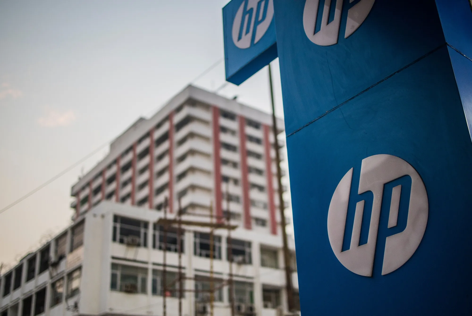 The HP Inc. logo with the backdrop of office buildings at Nehru Place IT Market in New Delhi, India, on Sunday, Dec. 12, 2021.&nbsp;