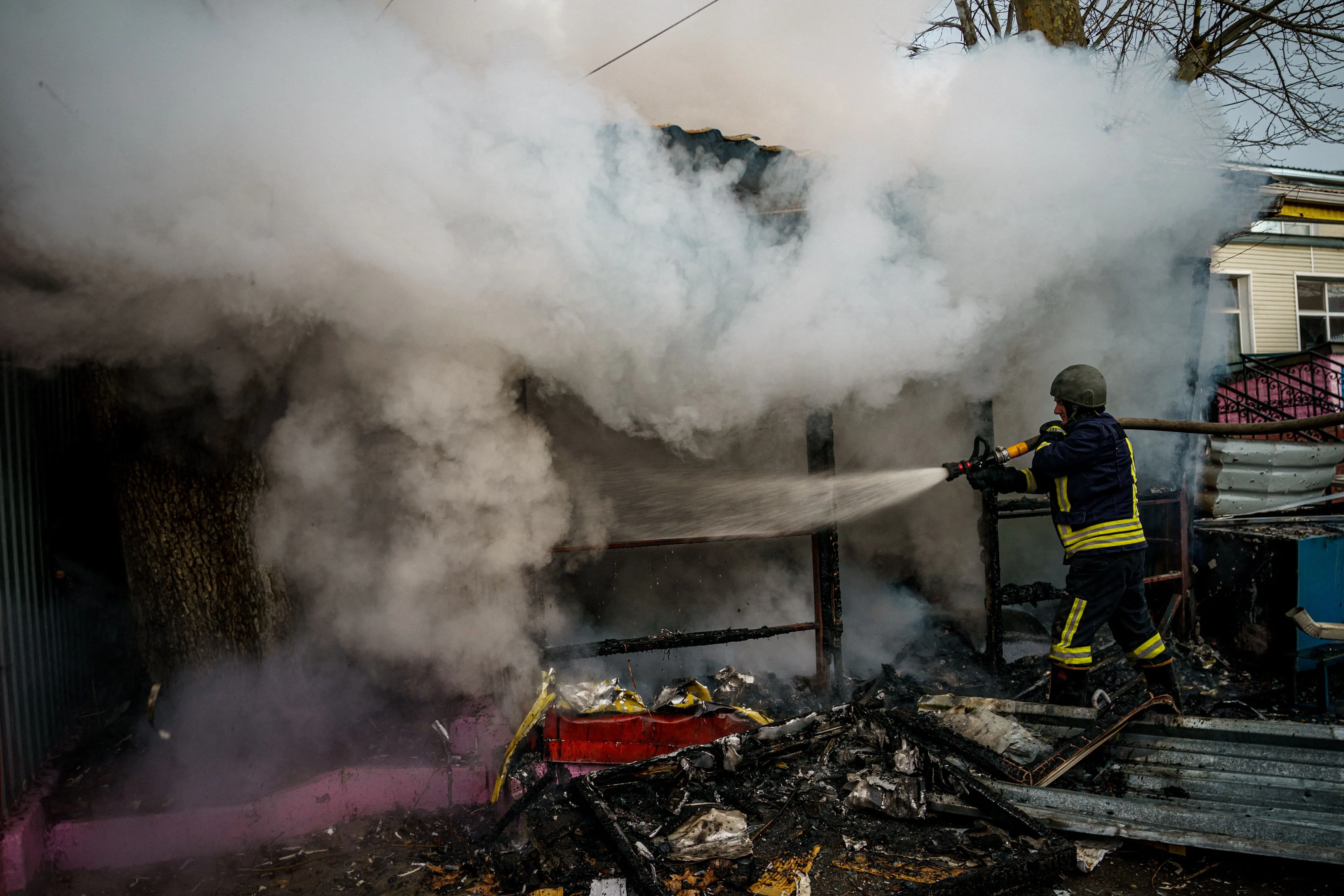 A rescuer extinguishes a fire in a burning shop after Russian shelling to Kherson, Ukraine,&nbsp;on Dec. 24, 2022.