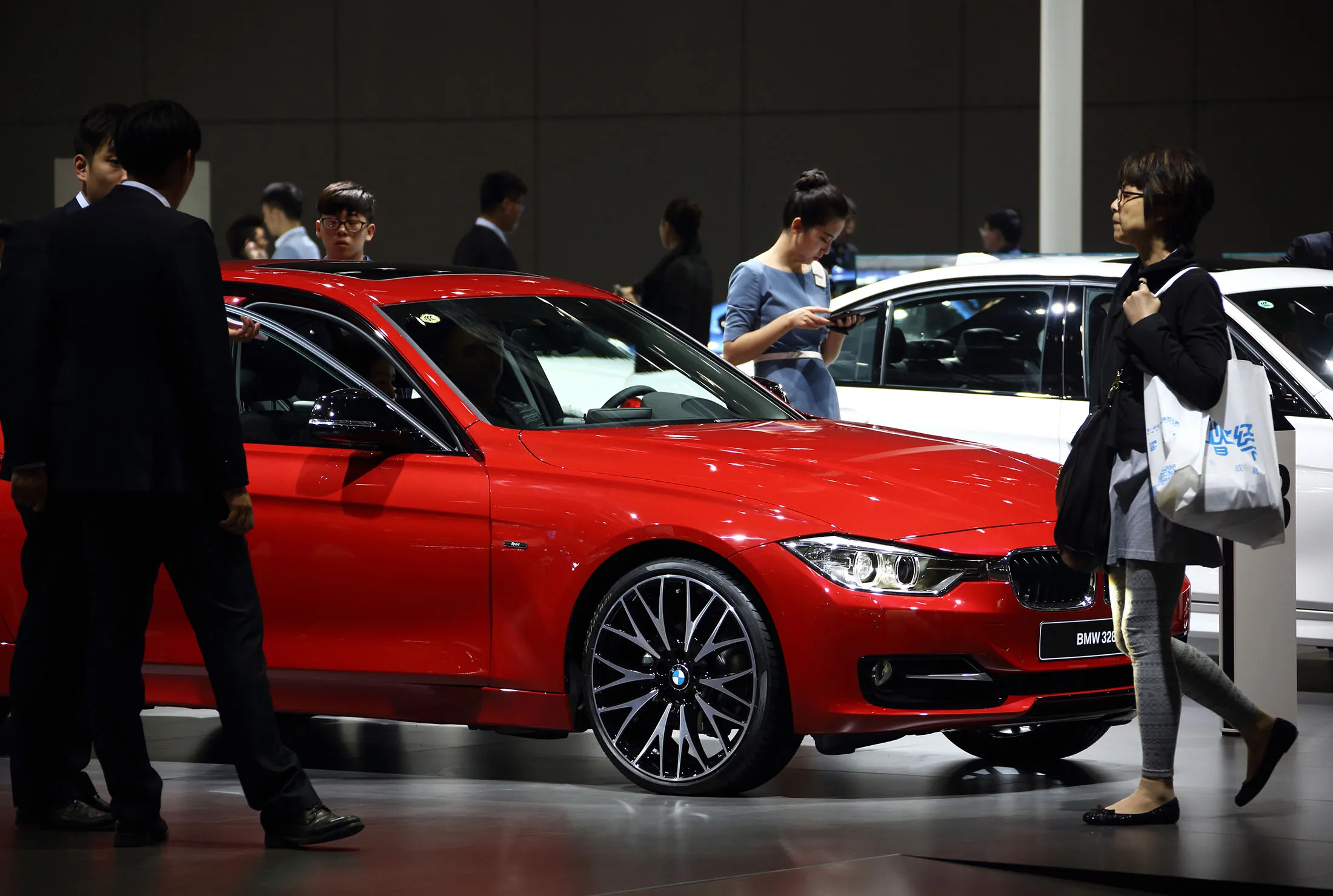 Visitors walk among BMW AG vehicles at Auto Shanghai 2015.
