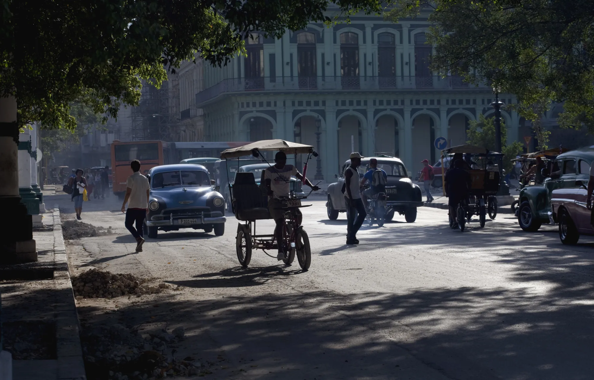 People and vehicles cross a street in Havana.
