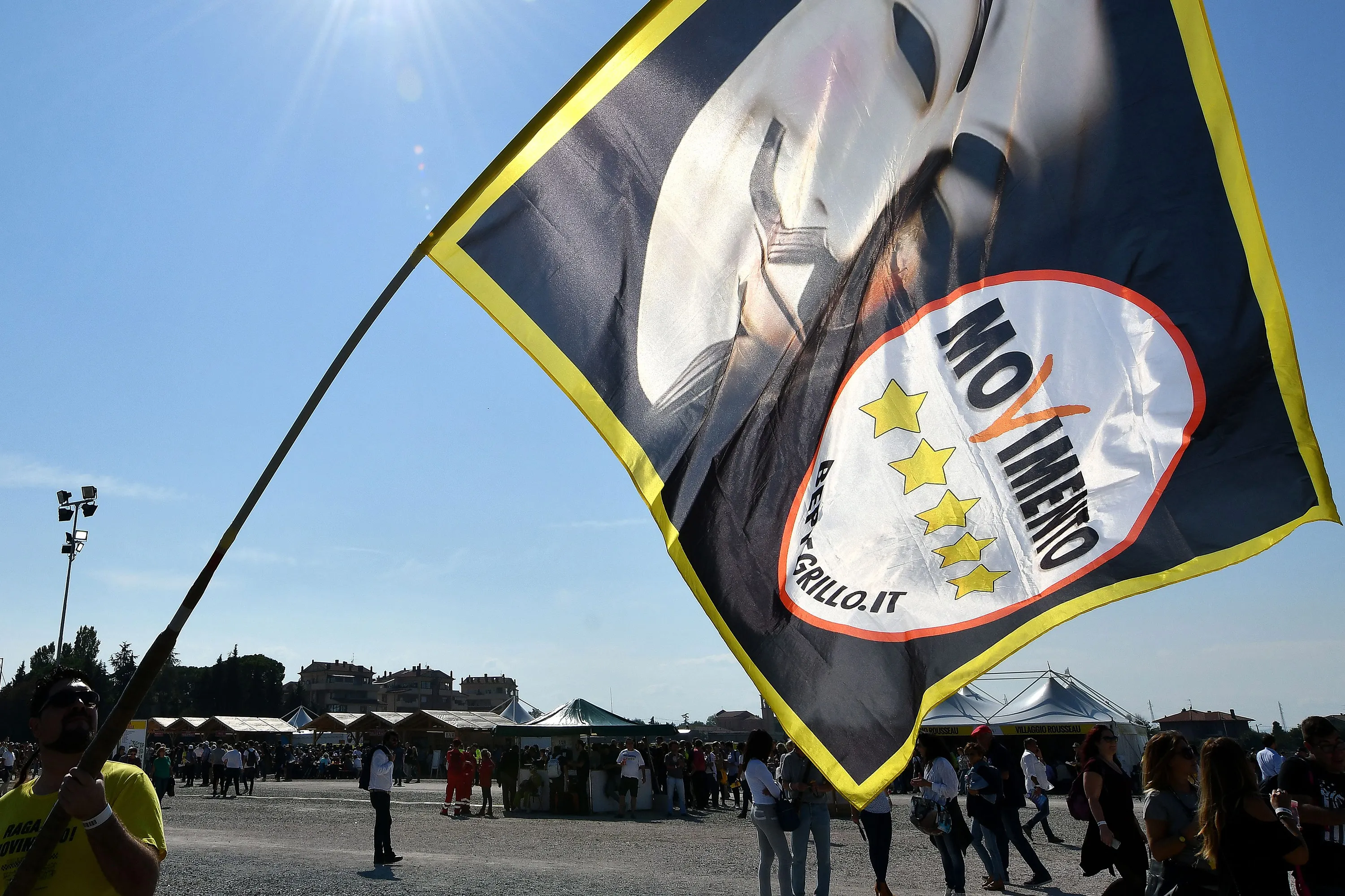 A supporter holds a Five Star Movement flag.