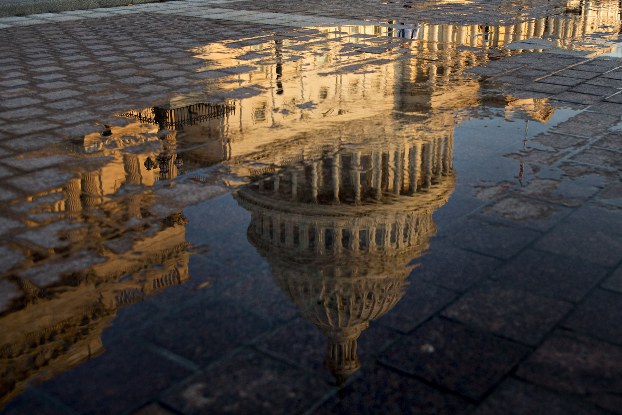 The U.S. Capitol building is reflected in a puddle at sunrise in Washington, D.C., U.S., on Wednesday, July 19, 2017. The Senate early next week will consider the motion to proceed to legislation to repeal Obamacare without finding a replacement for two years after a setback for Republicans' efforts this week to repeal and replace the bill. Senate Majority Leader McConnell said he's scheduling the vote at the request of President Trump and Vice President Pence.