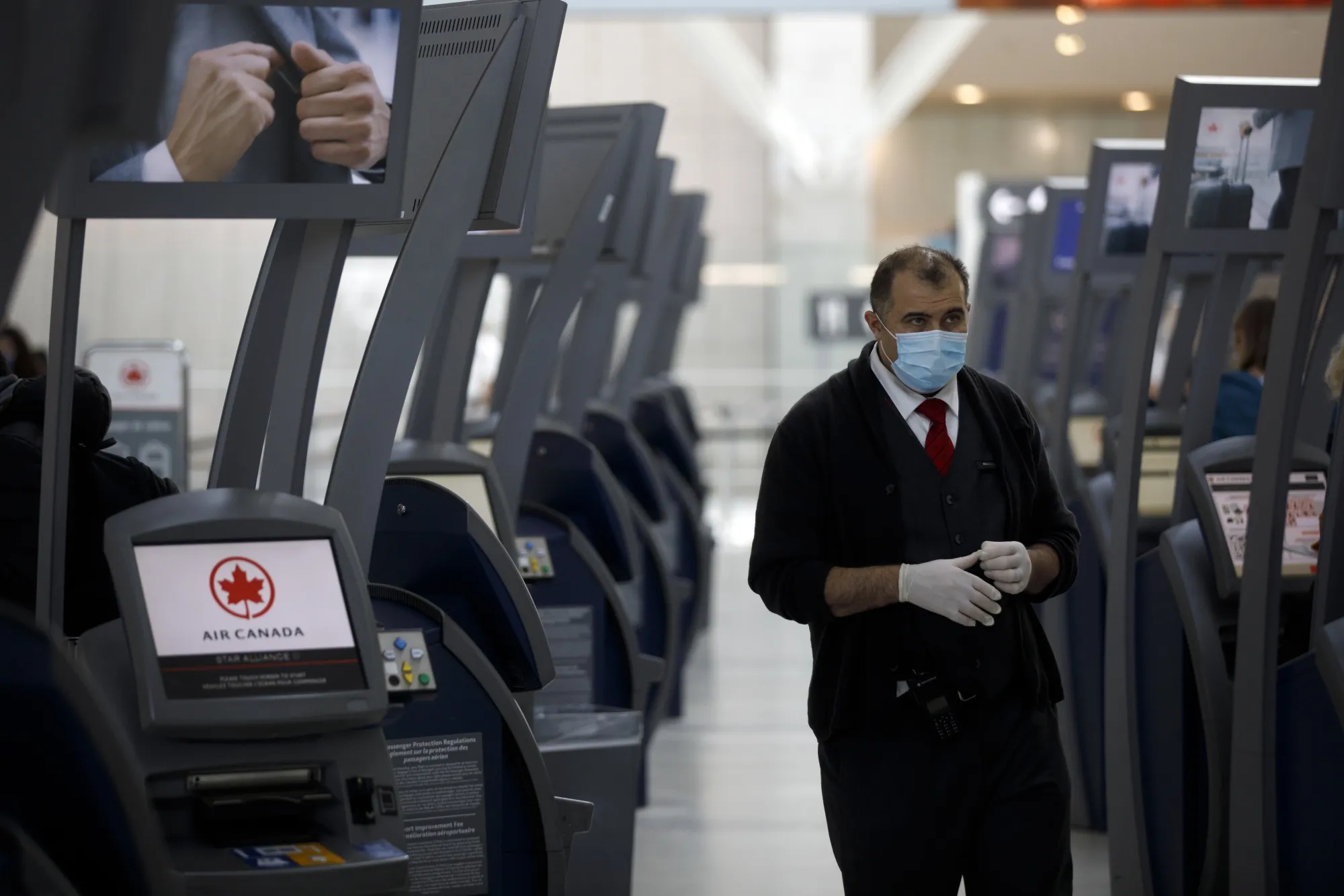 A gate agent waits to assist travelers at Air Canada check in terminals at Pearson airport in Toronto on March 16, 2020.