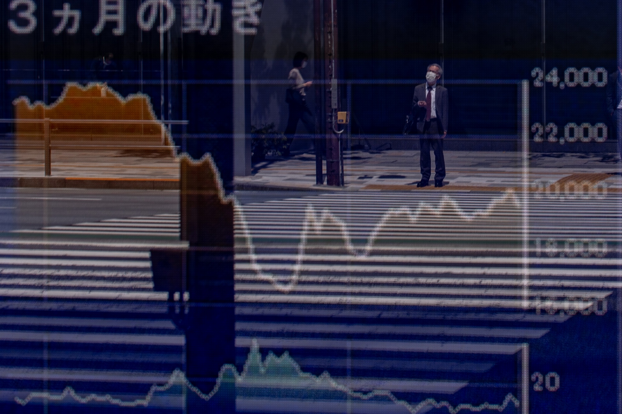 Pedestrians are seen reflected in a quotation board displaying stock on the Tokyo Stock Exchange in Tokyo.