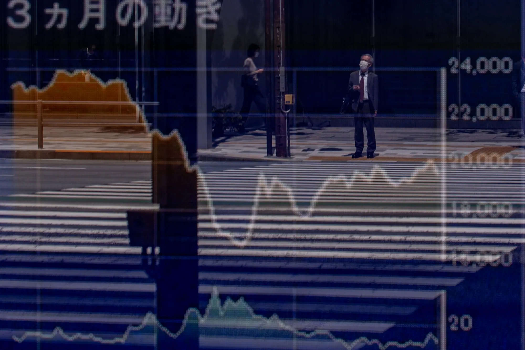 Pedestrians are seen reflected in a quotation board displaying stock on the Tokyo Stock Exchange in Tokyo.