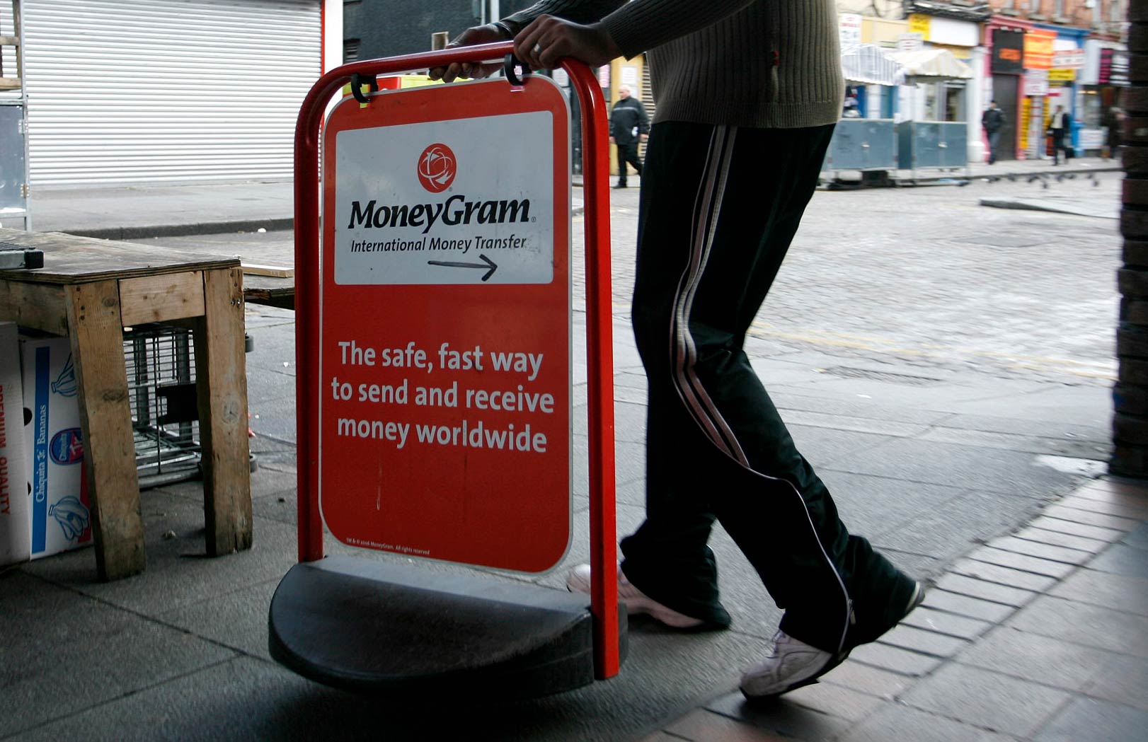 A shop worker places a sign for 'MoneyGram' outside his store on Moore Street in Dublin, Ireland.
