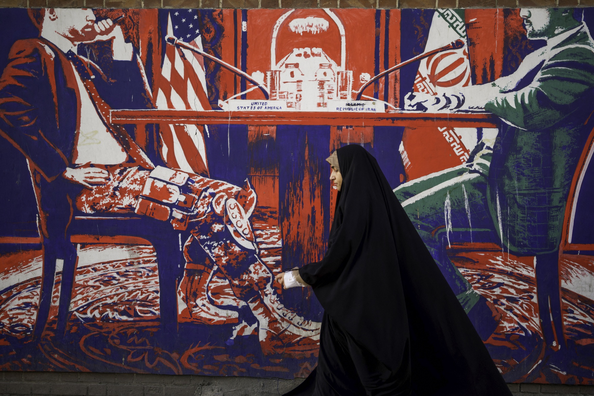 Iranians pass by the anti-American murals painted on the walls of the former embassy of the United States of America in Tehran, Iran on April 16, 2025, four days after Iran held the first round of indirect nuclear negotiations with President Trump's administration hosted and mediated by Oman. (Photo by Mohammadali Najib / Middle East Images / Middle East Images via AFP) (Photo by MOHAMMADALI NAJIB/Middle East Images/AFP via Getty Images)