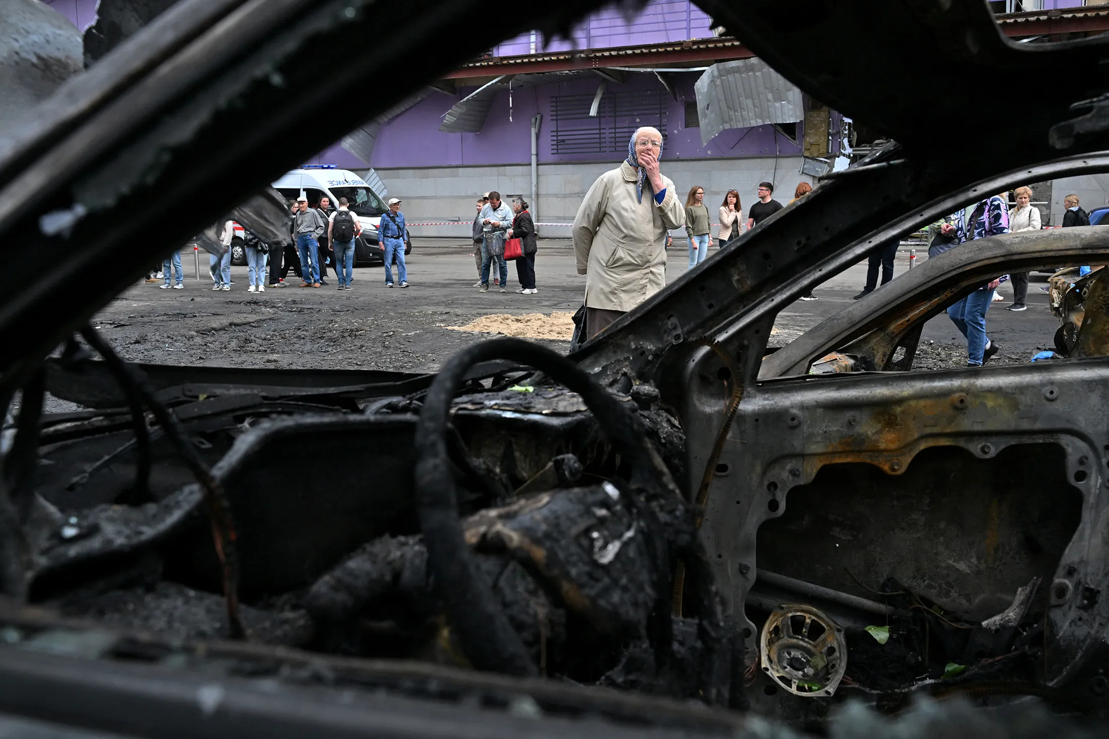 An elderly woman reacts as she looks at burned cars parked outside a mall following a night-time drone attack on Kyiv, on May 4.