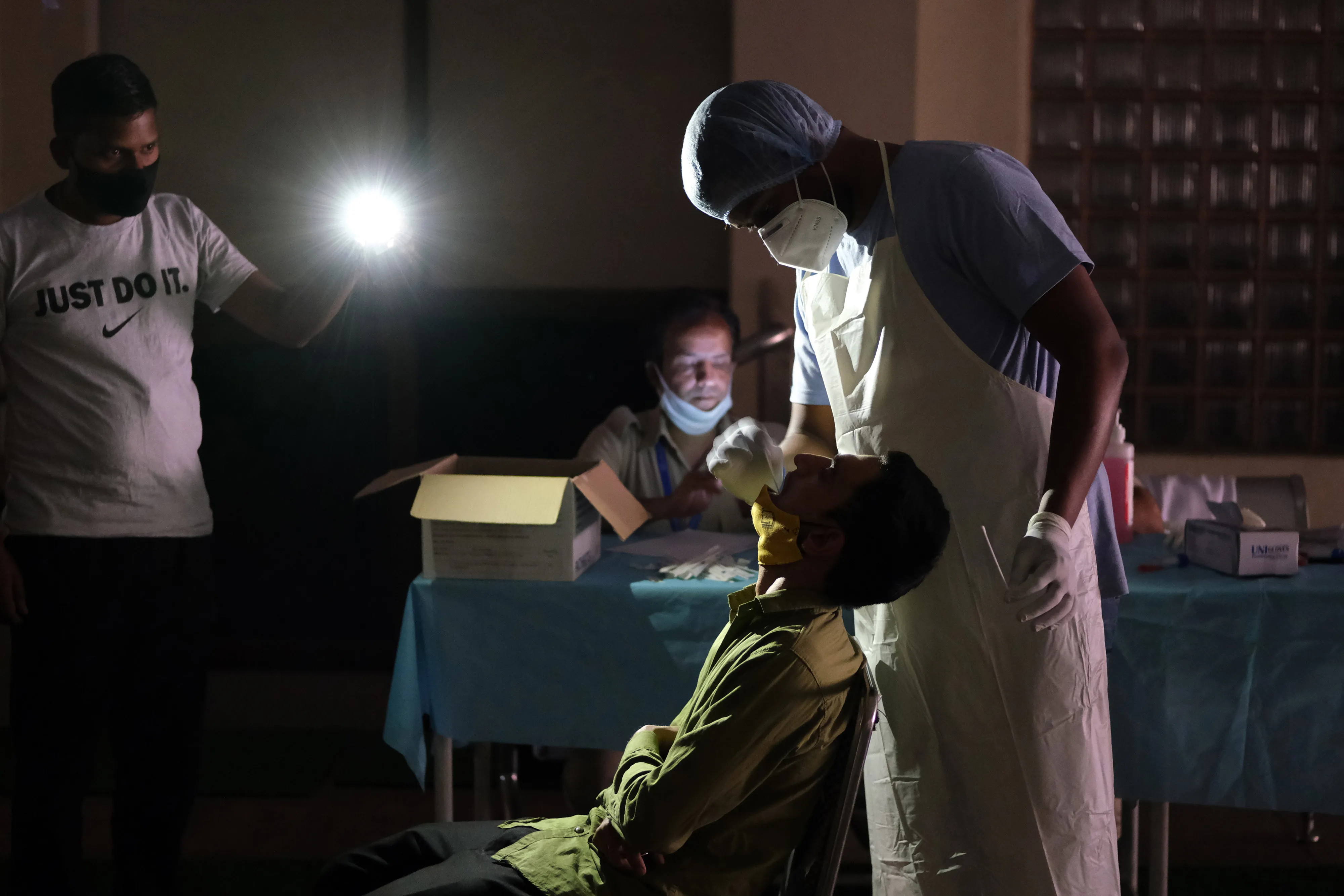 A health worker takes swab samples under the&nbsp;light of a colleague’s mobile phone at the Jawahar Lal Nehru Stadium in New Delhi, on April 16.