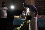 A health worker takes swab samples under the light of a colleague’s mobile phone at the Jawahar Lal Nehru Stadium in New Delhi, on April 16.