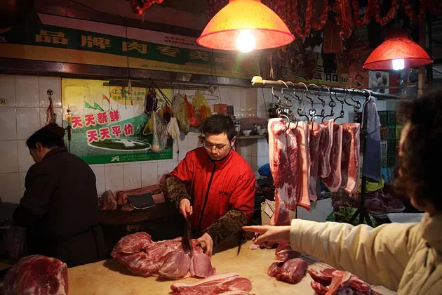 A customer requests for a cut of pork at a market in Shanghai, China