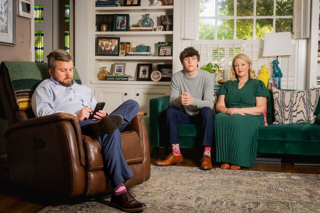 Ryan Turman sits on a chair, looking at his cell phone, as his son Hudson and wife Lacey sit nearby on a sofa in Amarillo, Texas