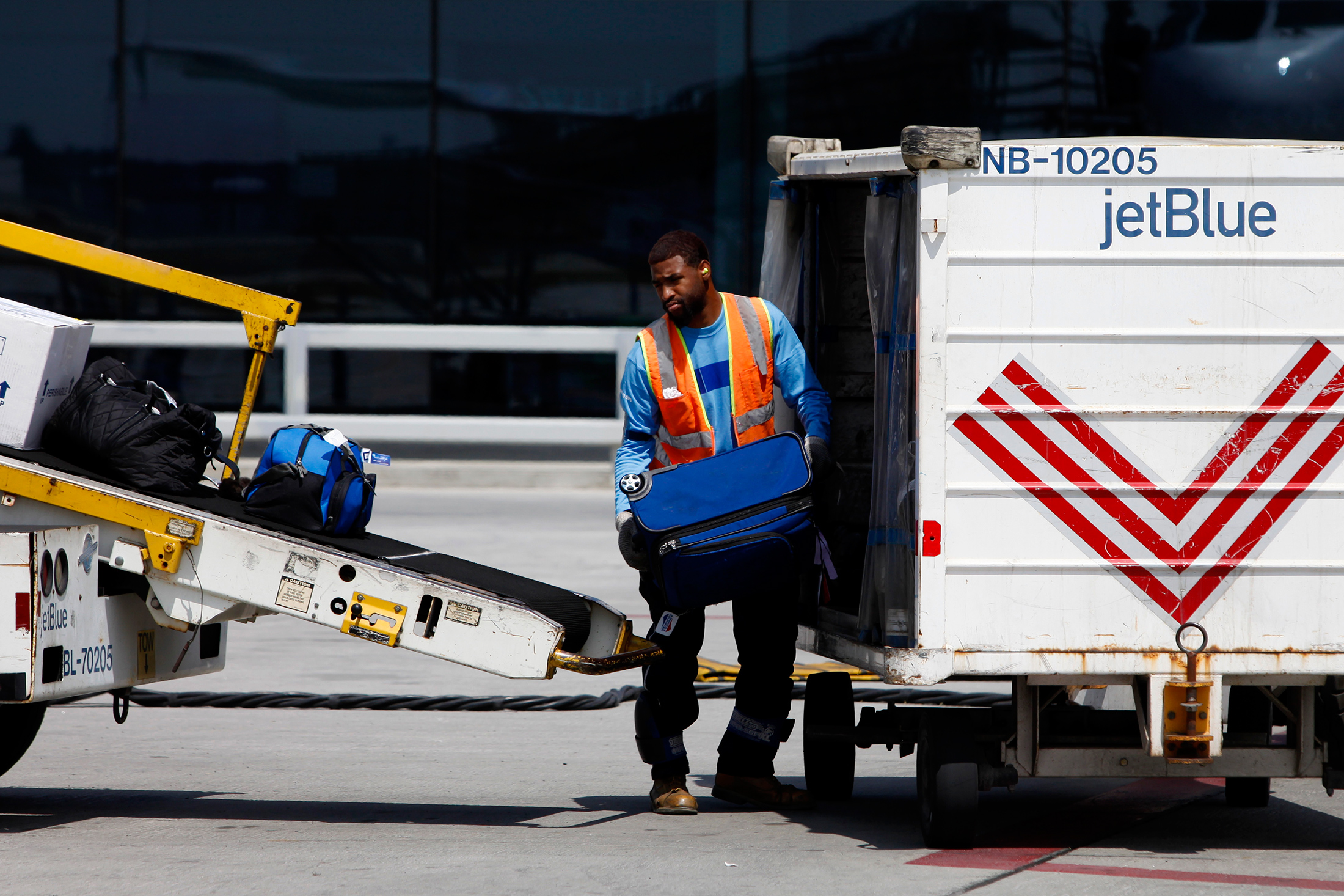A crew member loads baggage onto a JetBlue Airways Corp. plane at Long Beach Airport (LGB) in Long Beach, Calif. on July 22, 2013.
