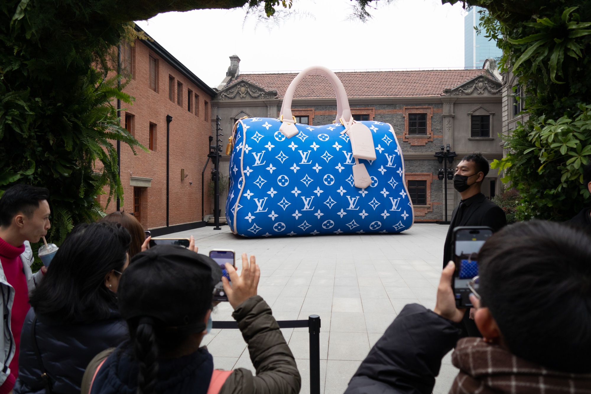 Bystanders photograph a giant Louis Vuitton bag on display in Shanghai. Luxury return rates in e-commerce obsessed China are increasing.