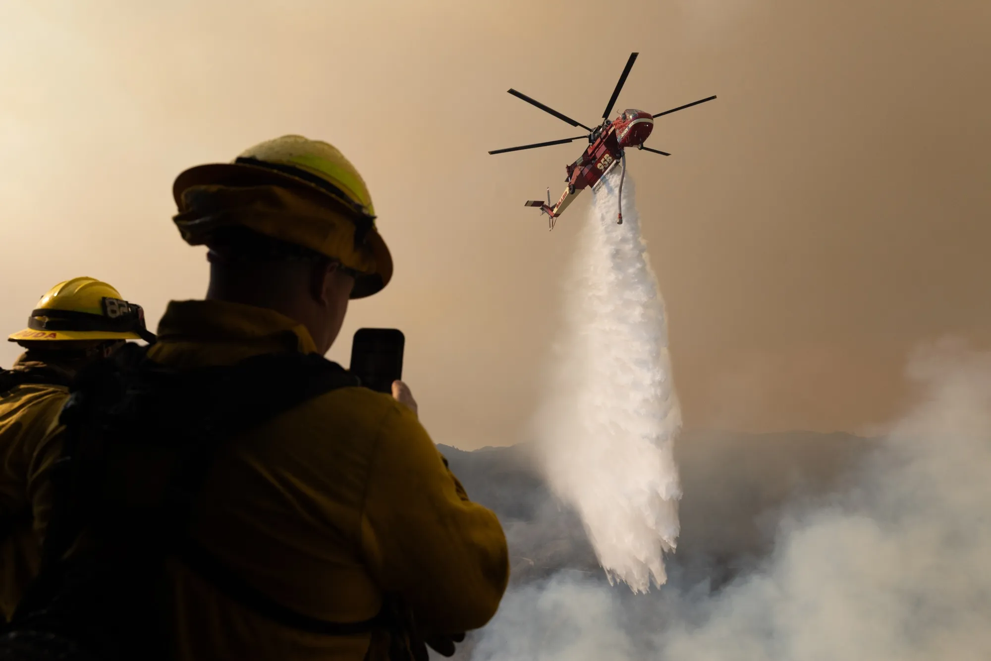 A helicopter drops water on the Palisades Fire near the Sullivan Canyon area on Jan. 11.