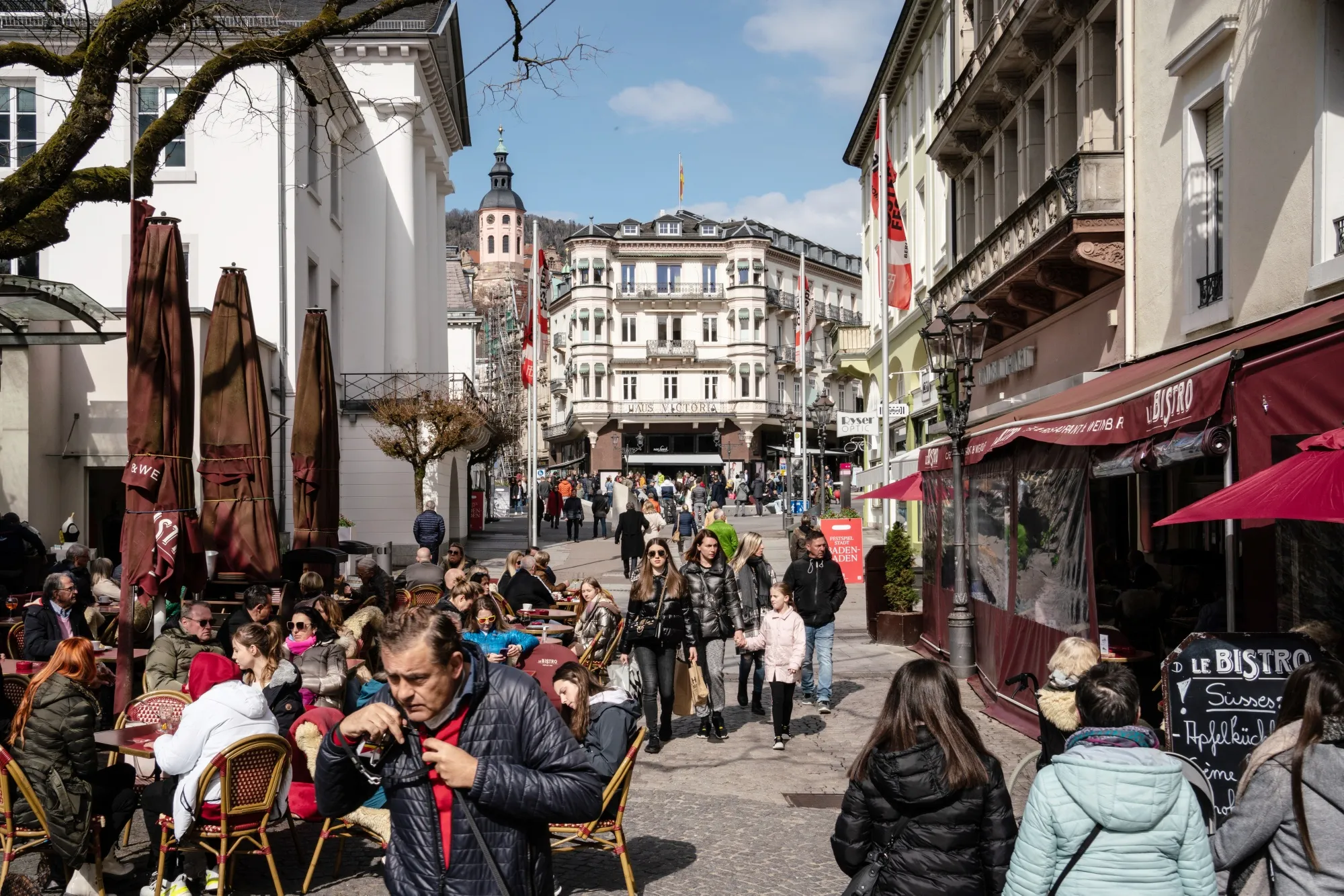Customers shop and dine on a busy street in Baden-Baden, Germany. US travel overseas has surged this year.