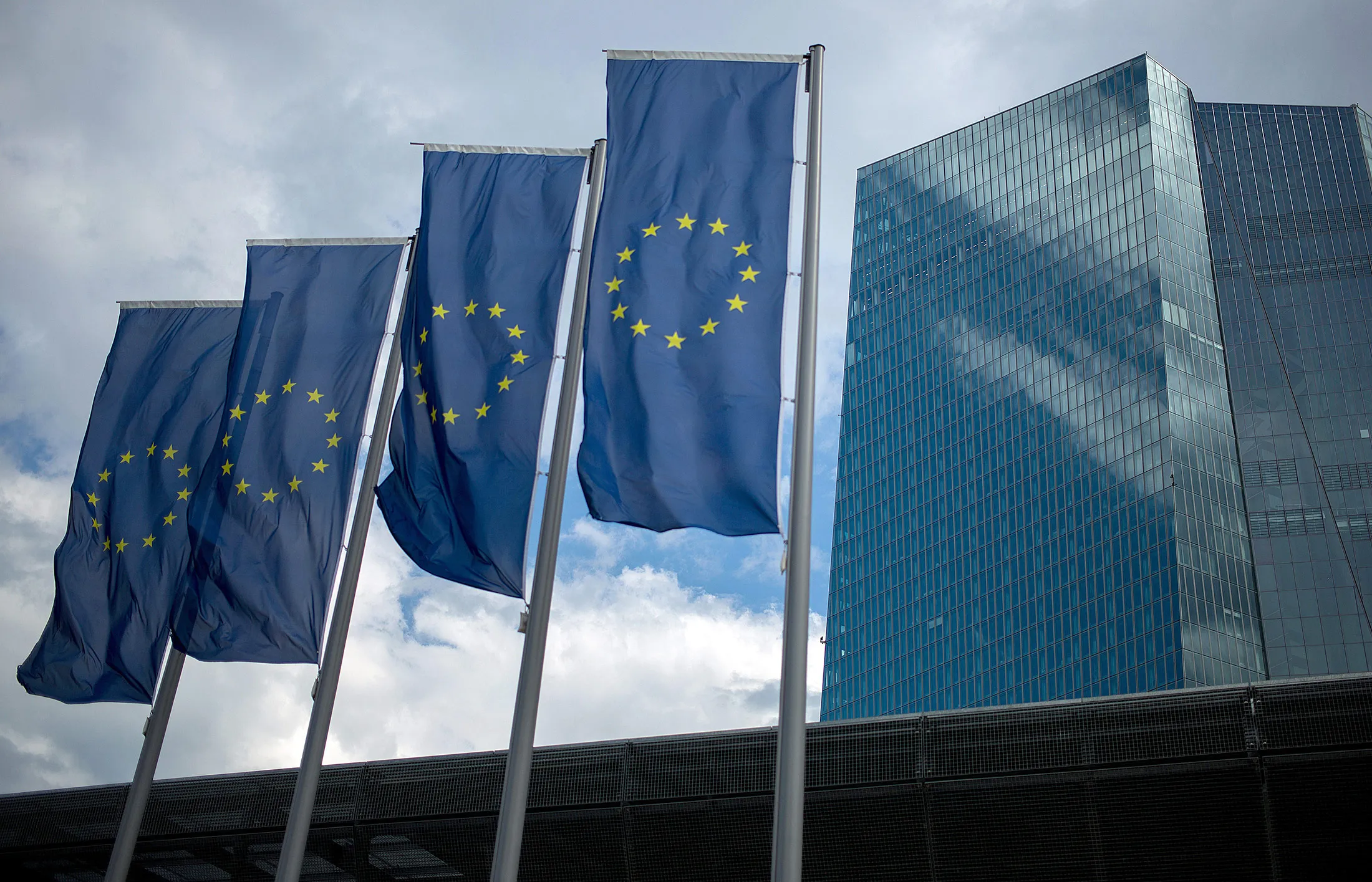 The stars of the European Union (EU) sit on banners flying outside the European Central Bank (ECB) headquarters stands in Frankfurt, Germany, on Thursday, July 20, 2017. Frankfurt has emerged as a winner of the Brexit vote, with Standard Chartered Plc, Nomura Holdings Inc., Sumitomo Mitsui Financial Group Inc. and Daiwa Securities Group Inc. picking the city as their EU hub in recent weeks.
