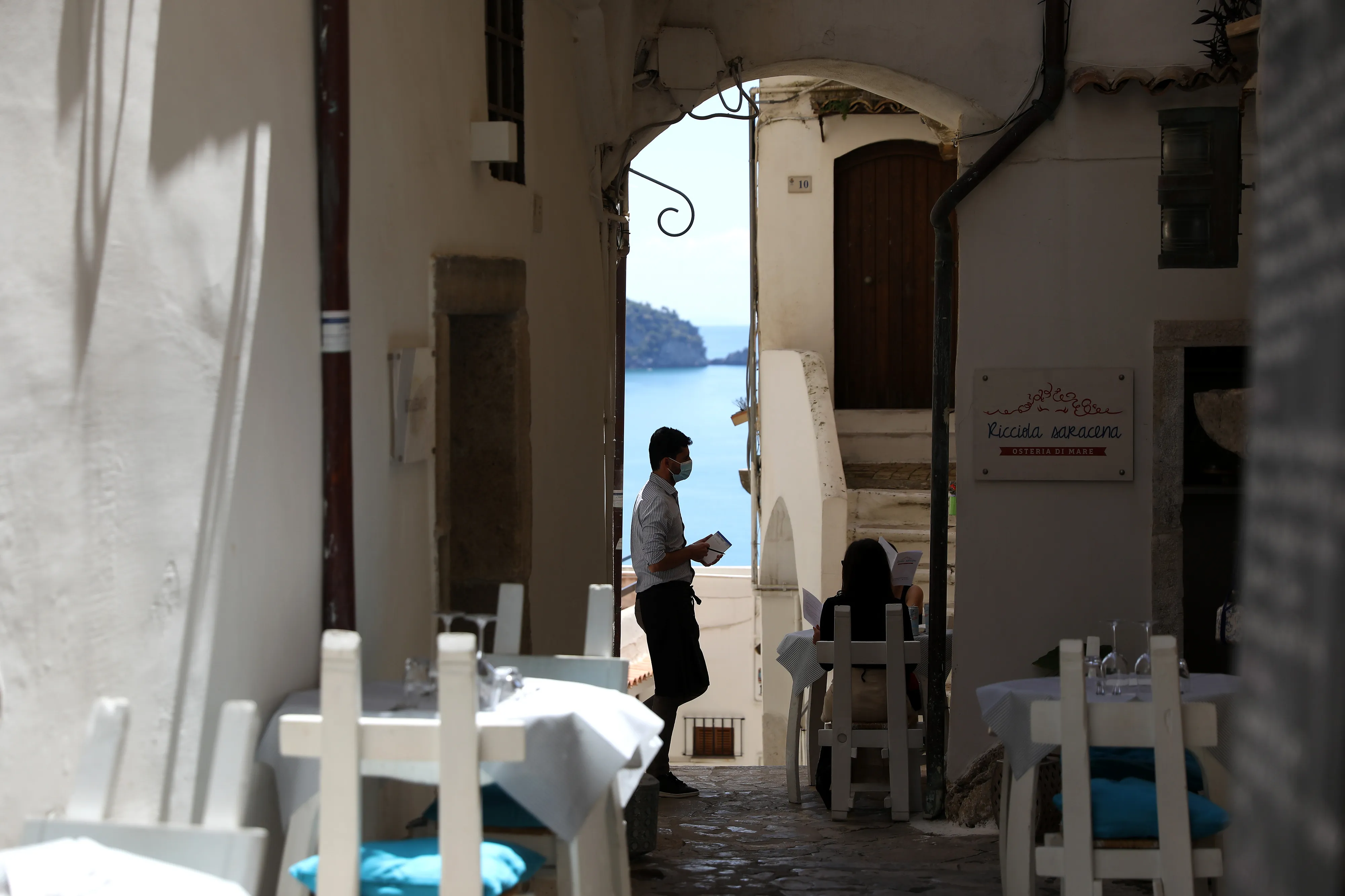 A waiter wearing a protective mask takes an order at a restaurant in the historic centre of the coastal town of Sperlonga, Italy, on&nbsp;May 31.&nbsp;