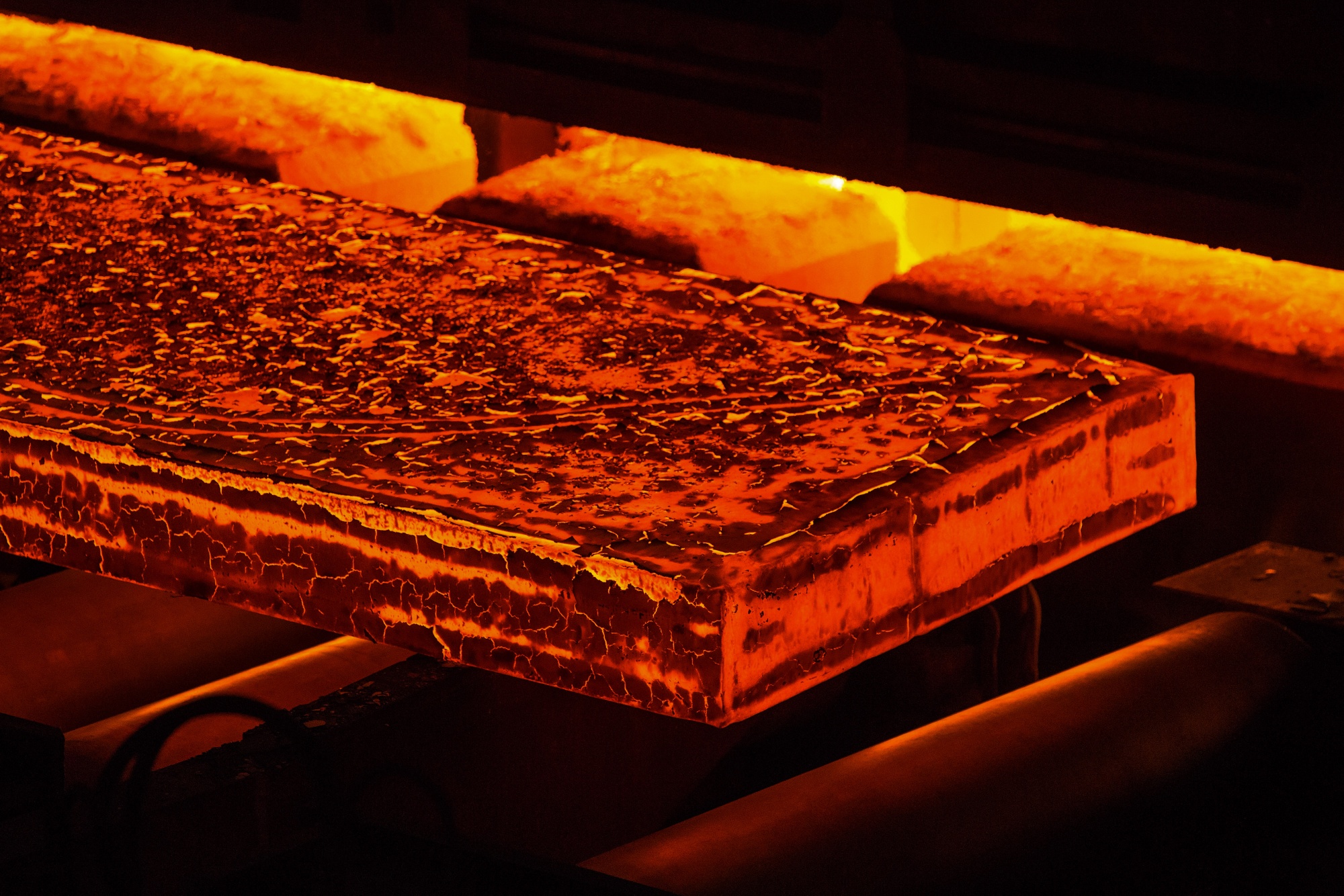 A red hot steel slab passes through a rolling mill.