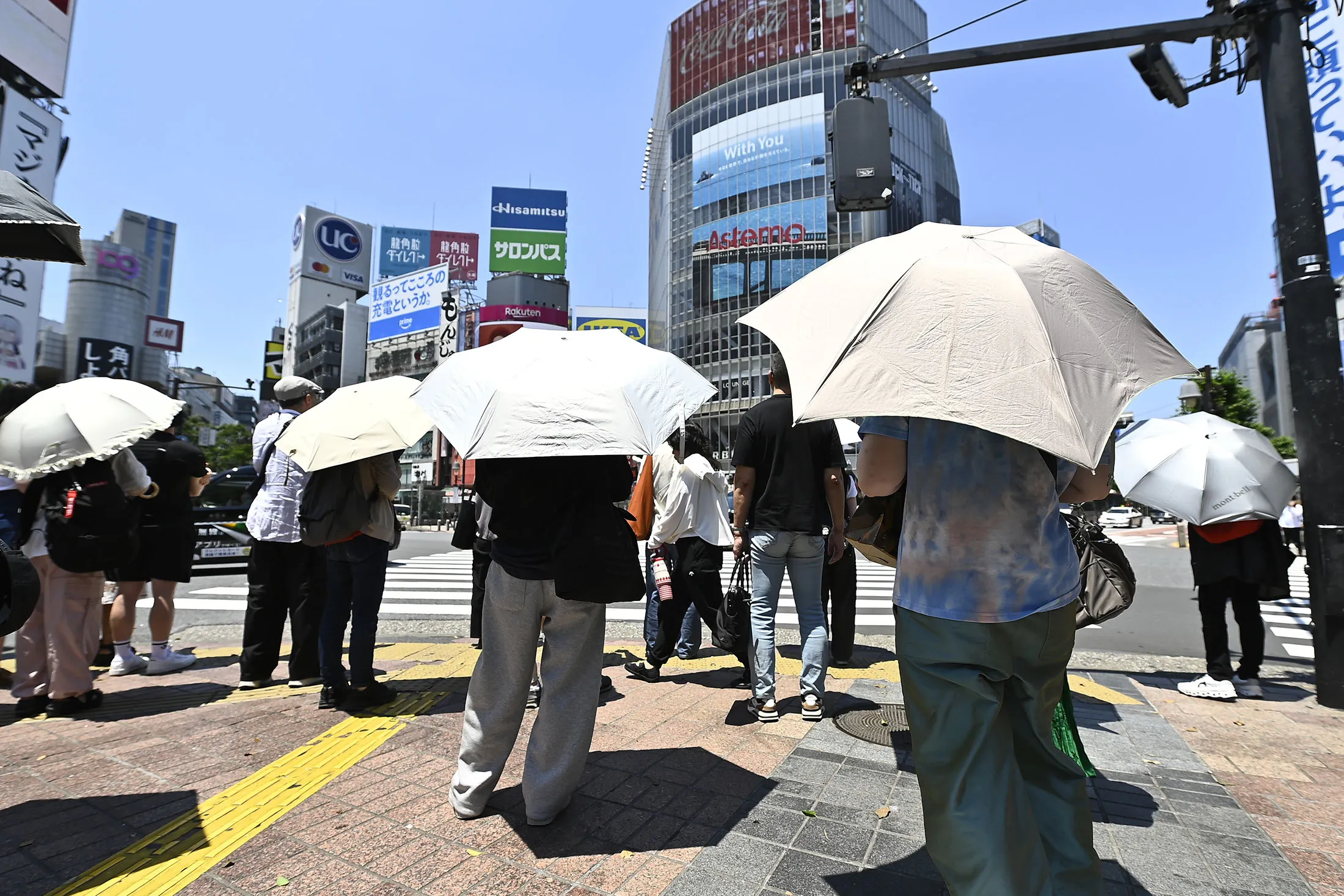 Pedestrians with parasols shield themselves from the sun in Tokyo, on June 17.