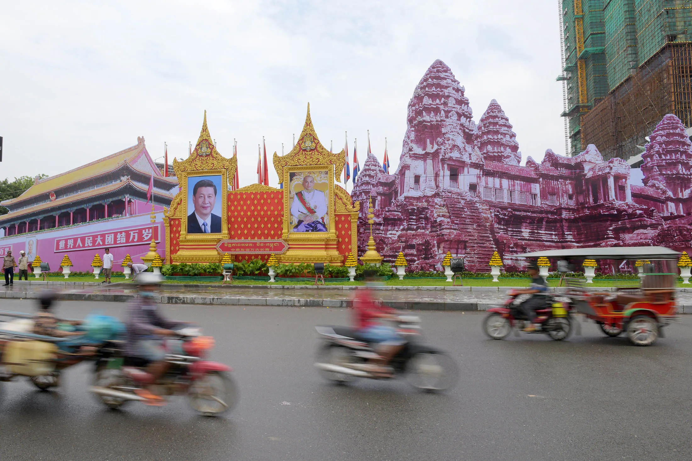 TOPSHOT - Motorists pass portraits of China's President Xi Jinping (L) and Cambodia's King Norodom Sihamoni in Phnom Penh on October 12, 2016. Xi is scheduled to arrive in Cambodia on October 13 for a two-day state visit. / AFP / TANG CHHIN SOTHY (Photo credit should read TANG CHHIN SOTHY/AFP/Getty Images)
