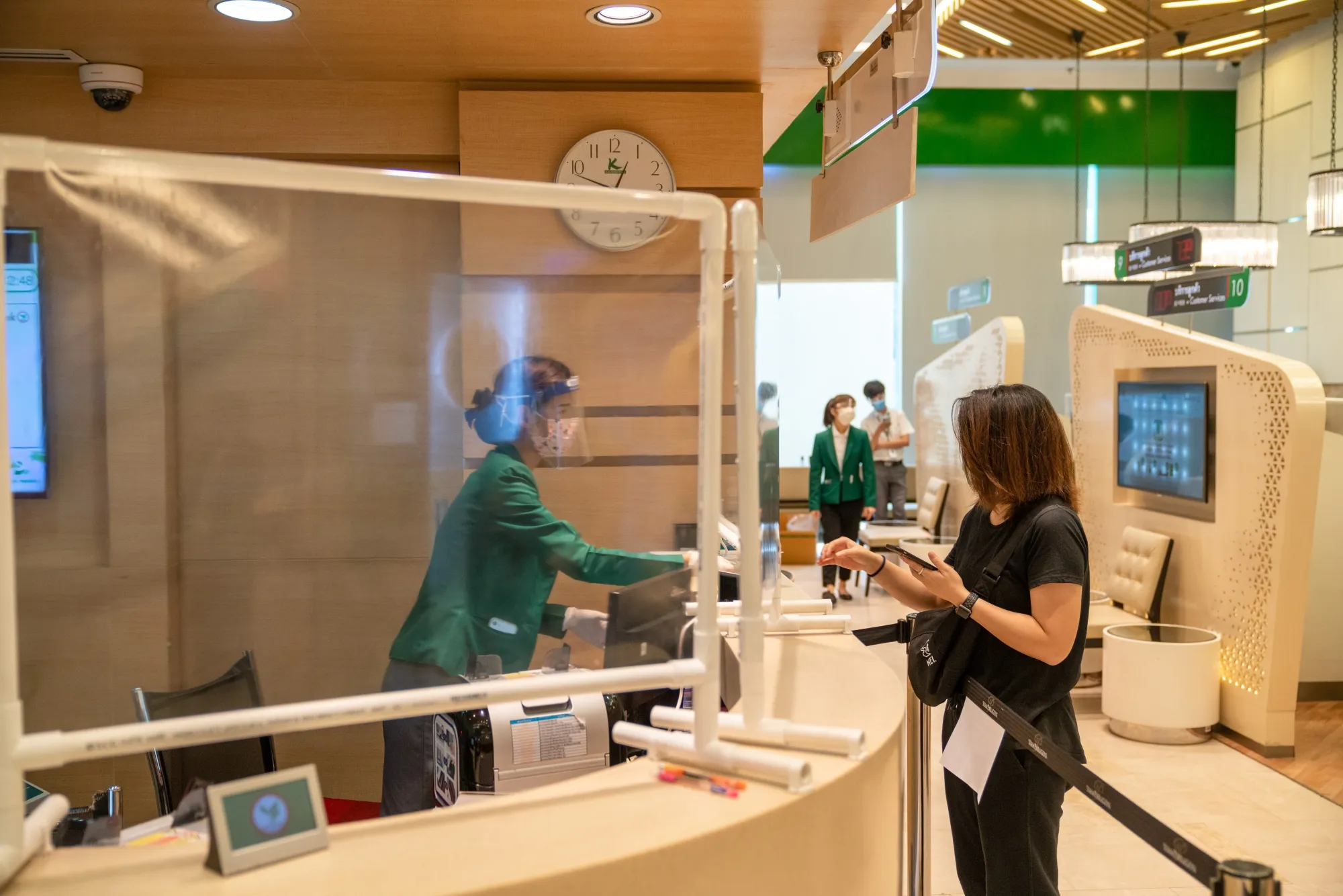 A bank teller attends to a customer at a Kasikornbank PCL branch&nbsp;in Bangkok.