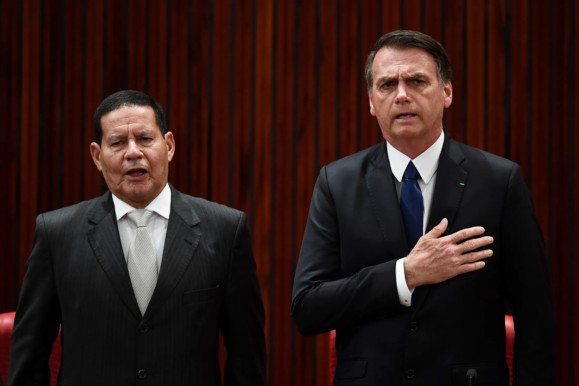 Jair Bolsonaro and his Hamilton Mourao listen to the national anthem at the TSE in Brasilia on Dec. 10.