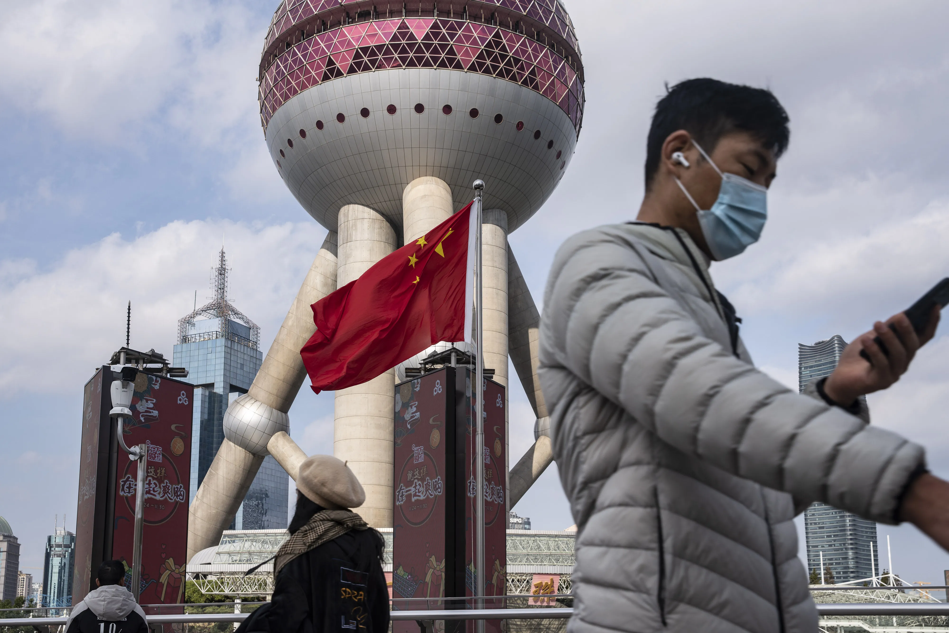Pedestrians walk past a Chinese flag in the Lujiazui financial district in Shanghai, China.