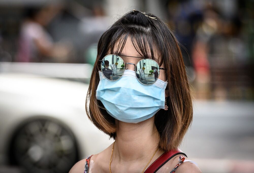 A woman wearing a protective facemask walks on a street in Bangkok on February 13, 2020. 