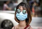 A woman wearing a protective facemask walks on a street in Bangkok on February 13, 2020.