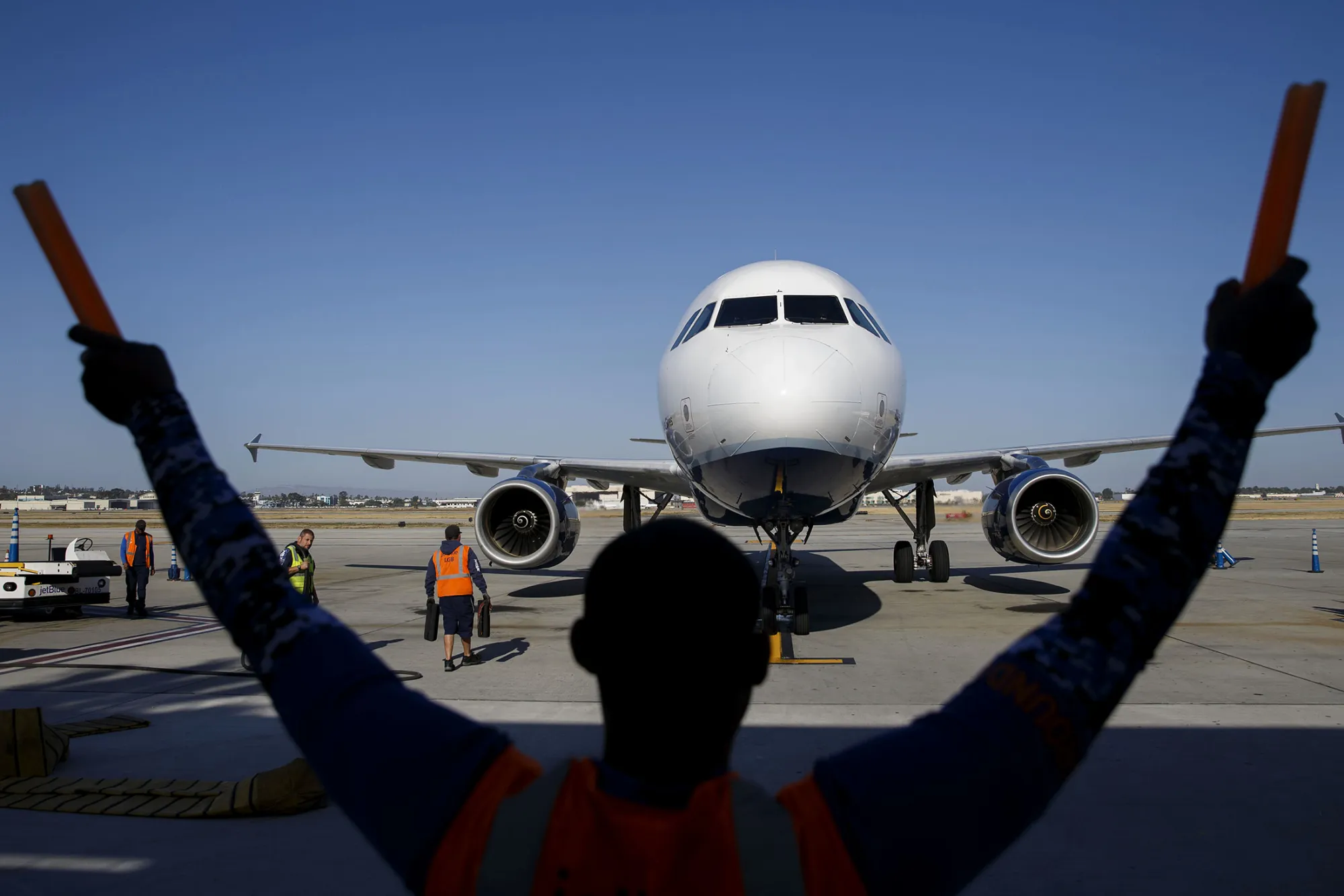 An aircraft marshaller guides a JetBlue Airways Corp. Airbus Group SE A320 aircraft on the tarmac at Long Beach Airport (LGB) in Long Beach, California, U.S., on Monday, April 25, 2016. JetBlue Airways Corp. is scheduled to release earnings figures on April 26.