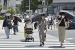 Pedestrians cross a street under the hot midday sun in Tokyo on June 30 