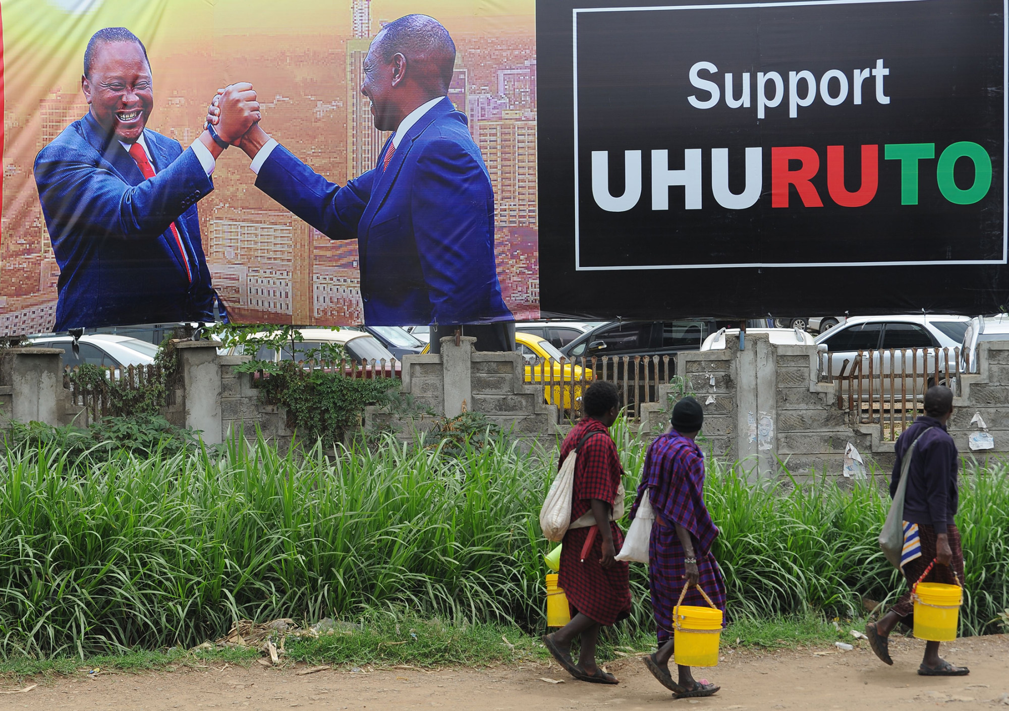 Pedestrians walk past a campaign poster for Uhuru Kenyatta and William Ruto in Nairobi on Oct. 23, 2017.
