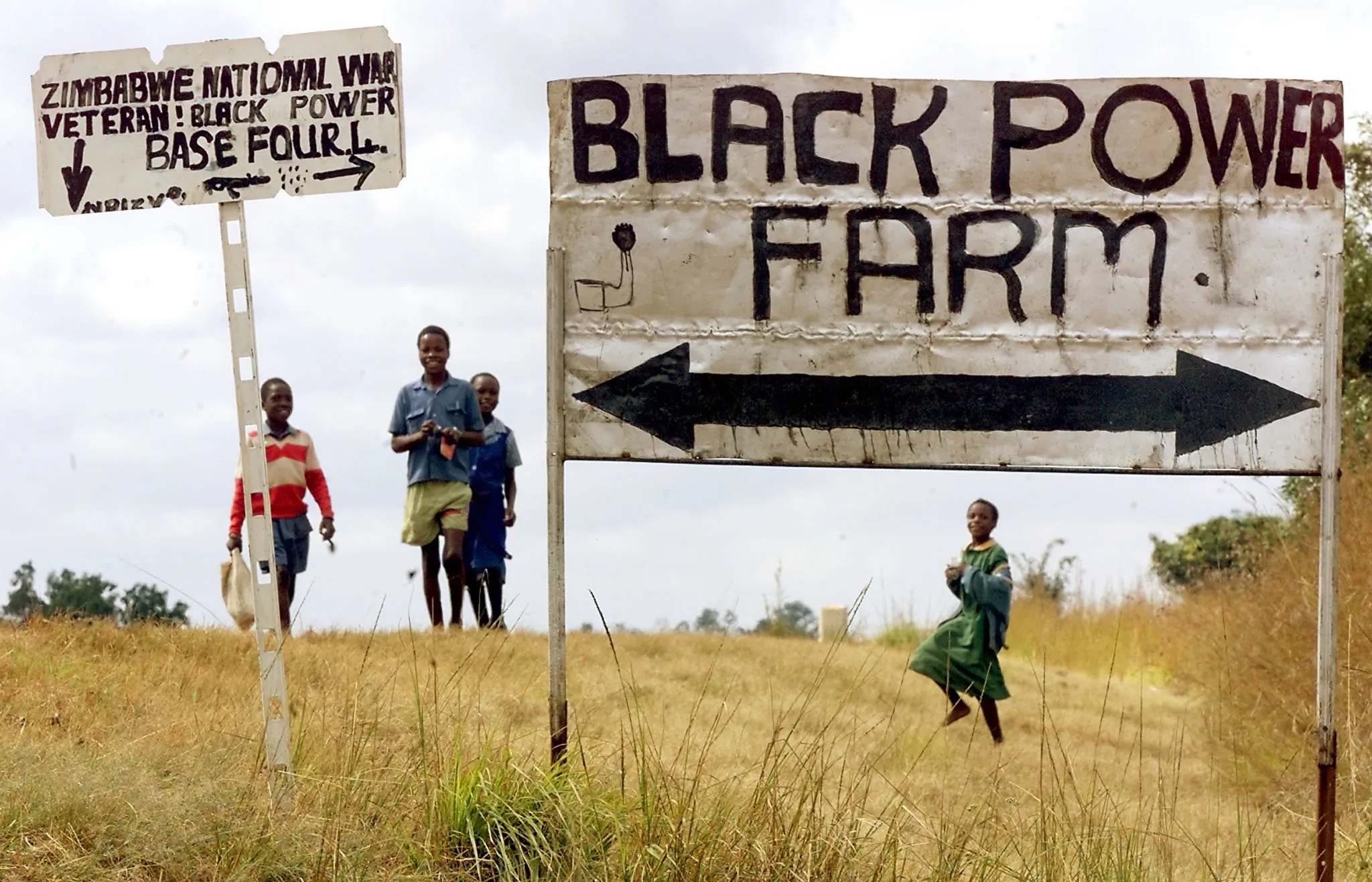 Schoolchildren pass the entrance of an occupied farm in Zimbabwe, in 2000.