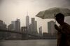 A pedestrian holding an umbrella walks through Main Street Park in the Brooklyn borough of New York, U.S., on Tuesday, May 28, 2019. Treasuries advanced, further inverting a key slice of the yield curve, while stocks fluctuated as investors positioned for what could be a protracted trade dispute with China.